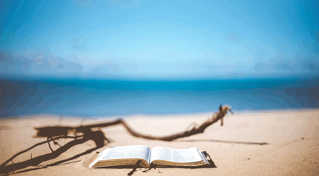 blurry beach scene with an open Bible in the sand